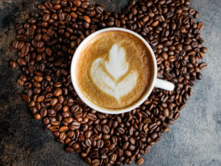 Top view cappuccino on a background of coffee beans in the form of a heart